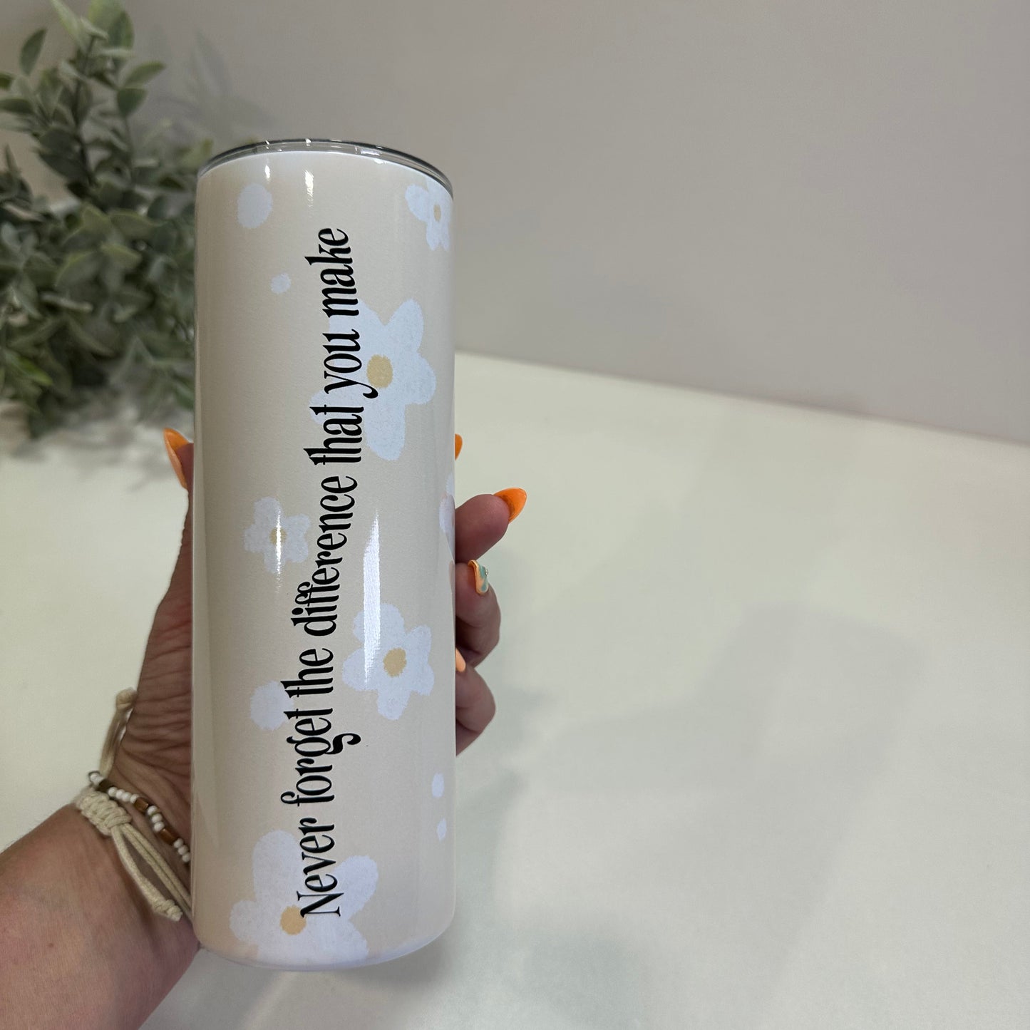 Tumbler with floral design and text held by a person against a neutral background