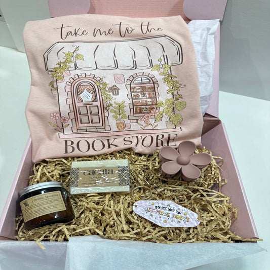 pink gift box with a take me to the bookstore peach shirt, a soap, a candle, a flower hair clip and a pink motel keychain that said on my way to get more books