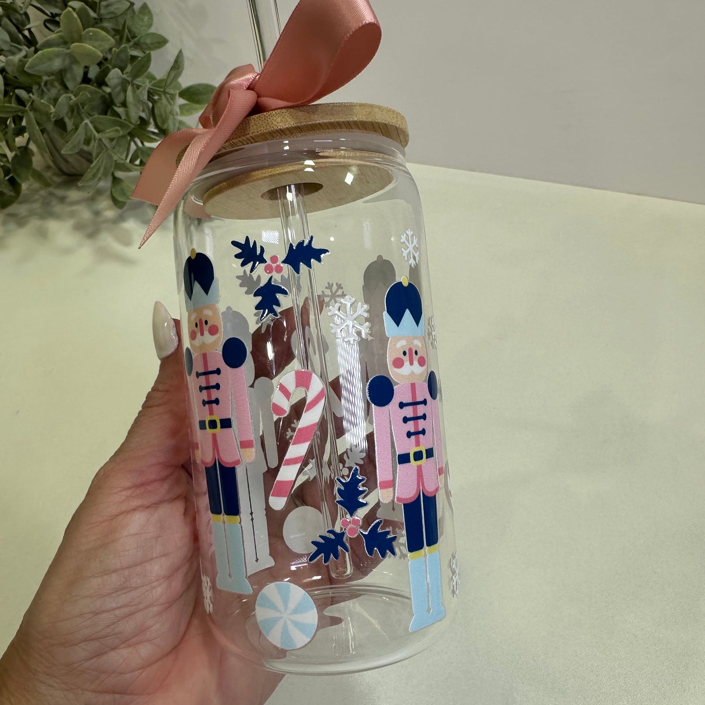 Clear tumbler with festive nutcracker design held by a hand against a neutral background