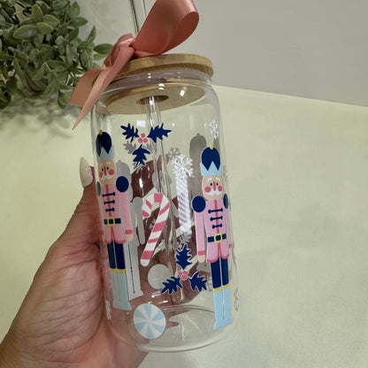 Clear tumbler with festive nutcracker design held by a hand against a neutral background
