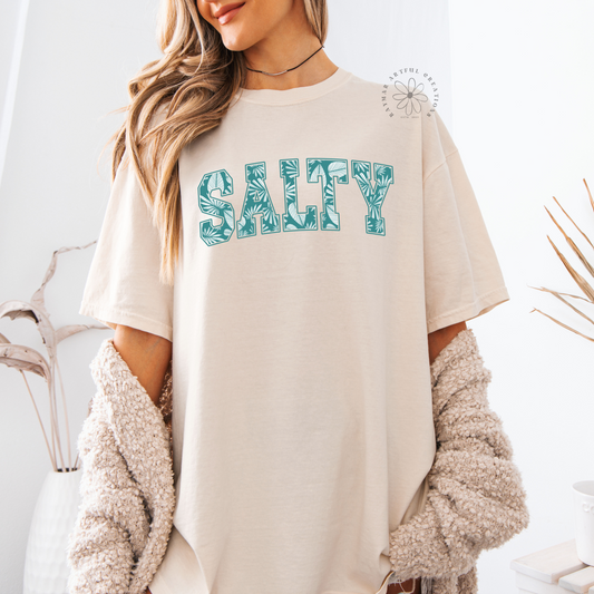 a women wearing an ivory shirt with a salty design in blue ocean colors with palms