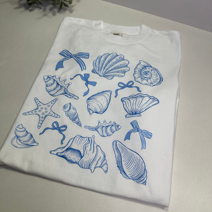 White t-shirt with blue sea-themed graphics on a white surface.