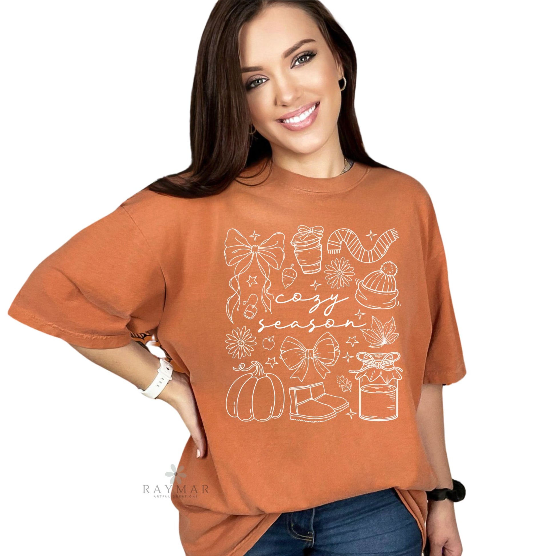 Woman wearing a rust-colored t-shirt with 'cozy season' graphic design on a white background