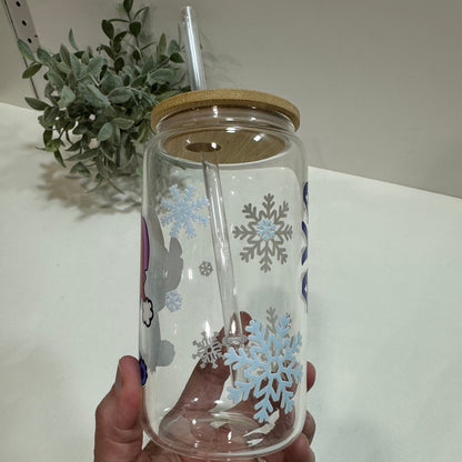 Clear tumbler with snowflake design held by a hand, with a plant in the background.