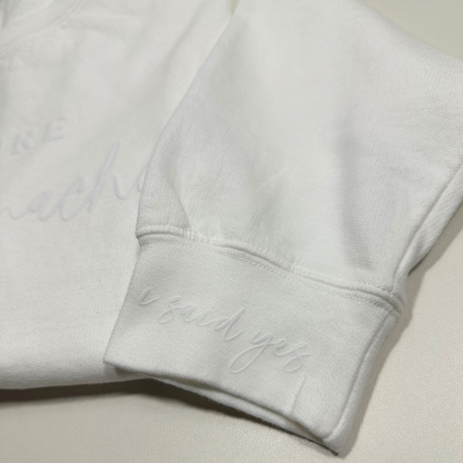 wrist of white sweatshirt that said i said yes in embossed design