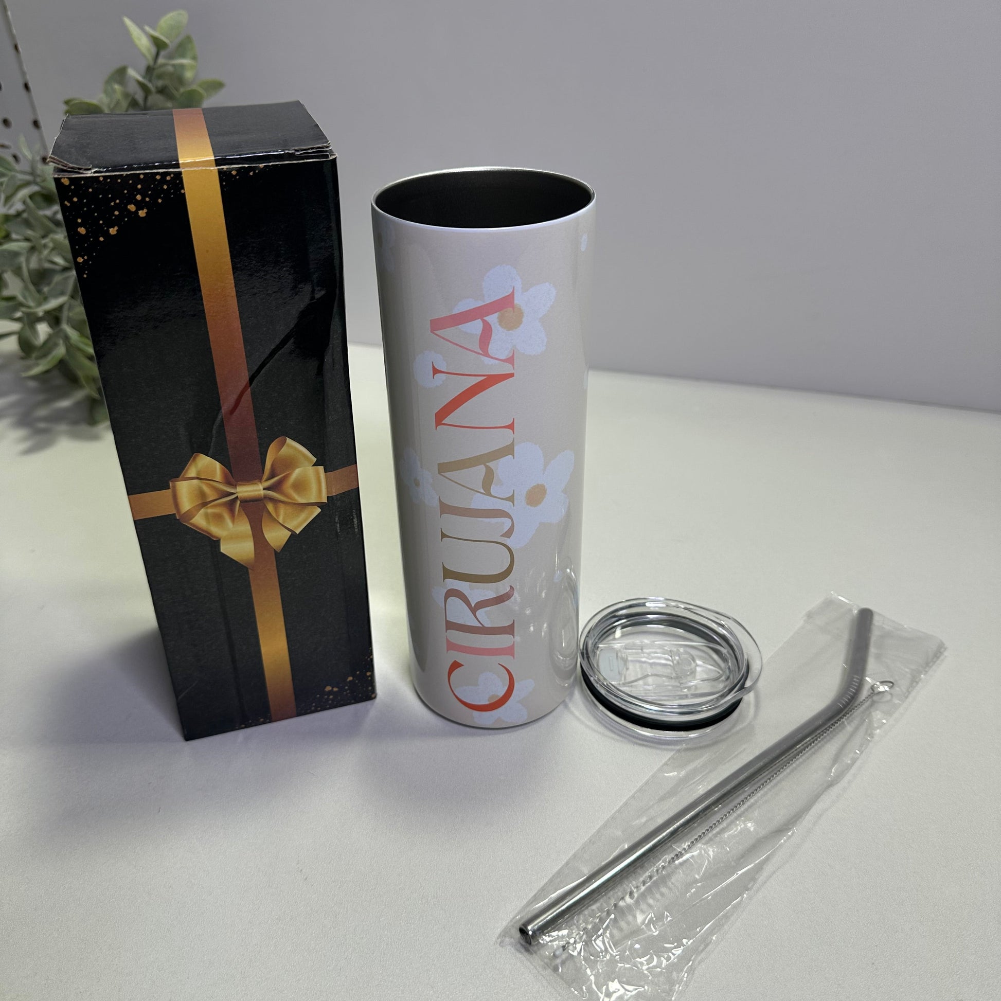 Custom tumbler product packaging with a cylindrical container, clear lid, and black box with gold ribbon on a white background.