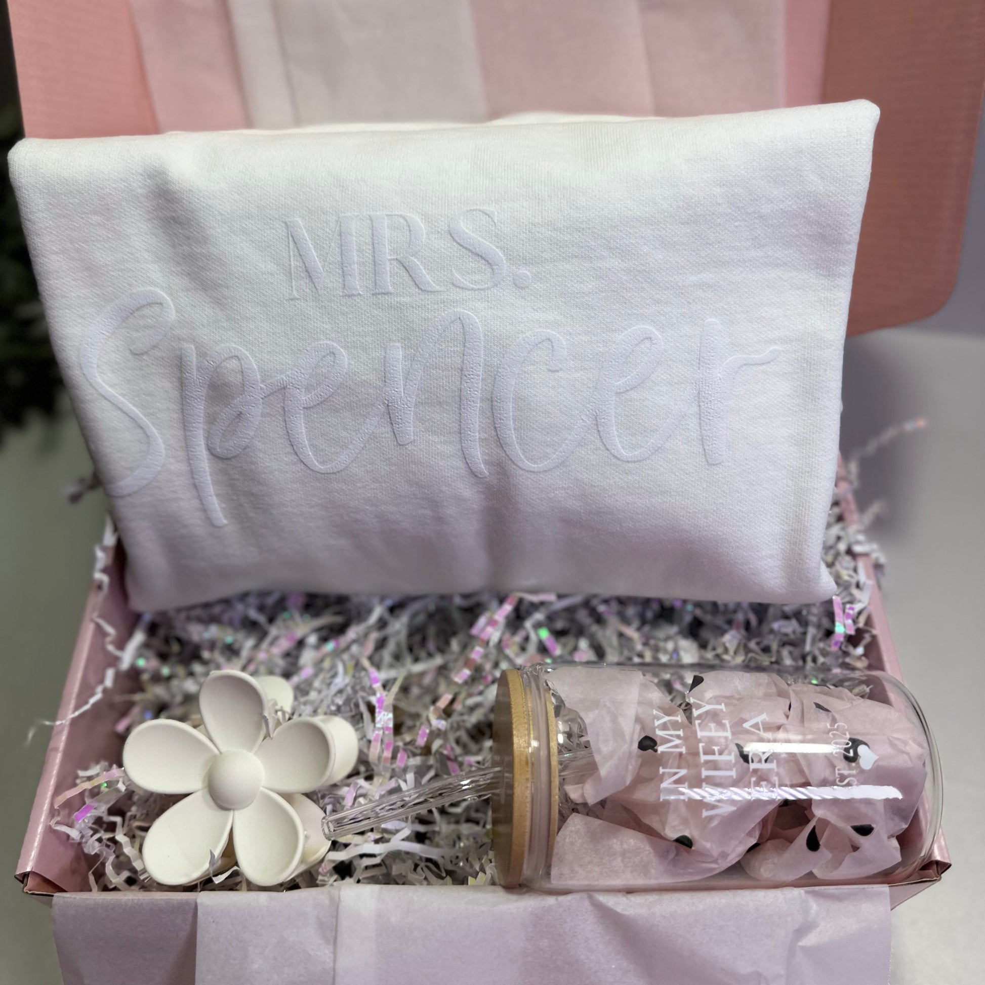Gift box with white Mrs. persoanlized sweatshirt , flower hair clip, in my wifey era glass cup and a pink background