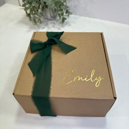 kraft box with name in gold and a dark green bow