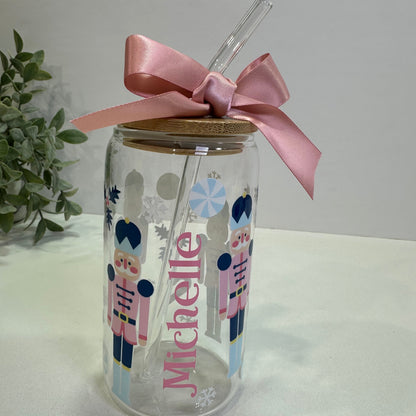 Glass jar with nutcracker design and pink ribbon on a white background
