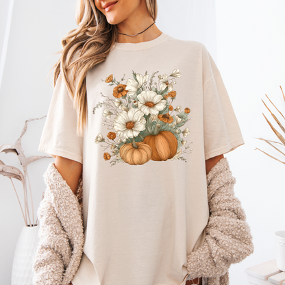 Person wearing a beige t-shirt with a floral and pumpkin design.