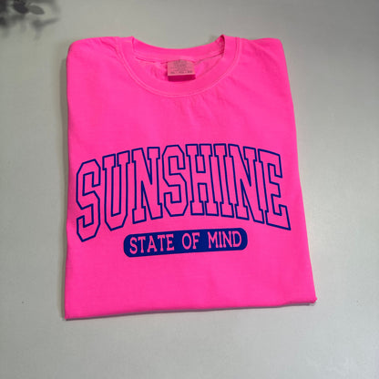 Pink t-shirt with 'Sunshine State of Mind' text on a gray surface