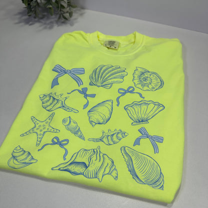 Neon yellow t-shirt with blue shell and starfish patterns on a white background